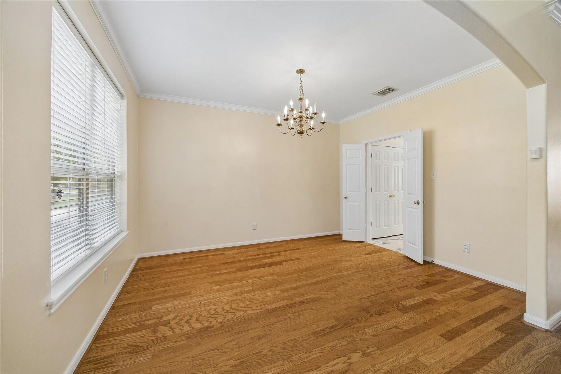 1115 Mulberry Lane, Bellaire, TX 77401 Elegant dining room with warm wood flooring, a classic chandelier, and ample natural light from a large window.