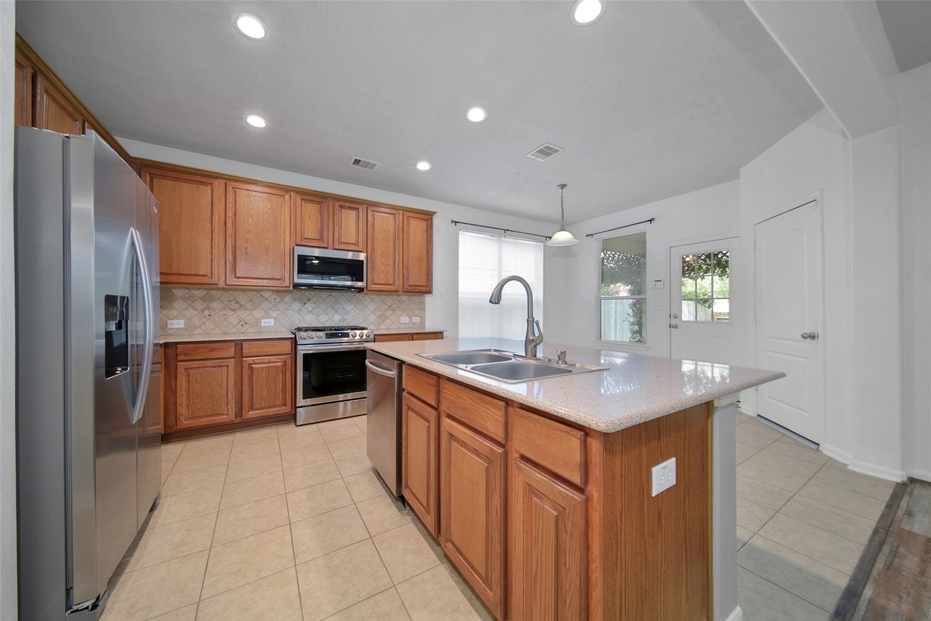 The kitchen is functional and pretty! Quartz countertops, Island with breakfast bar, stainless steel appliances, recessed lighting and adjacent pantry and utility room.