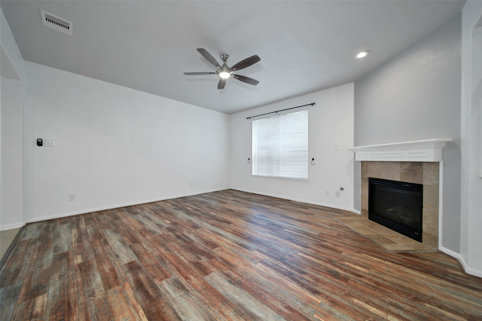 Living room features wood laminate flooring, a cozy gaslog fireplace and is open to the kitchen.
