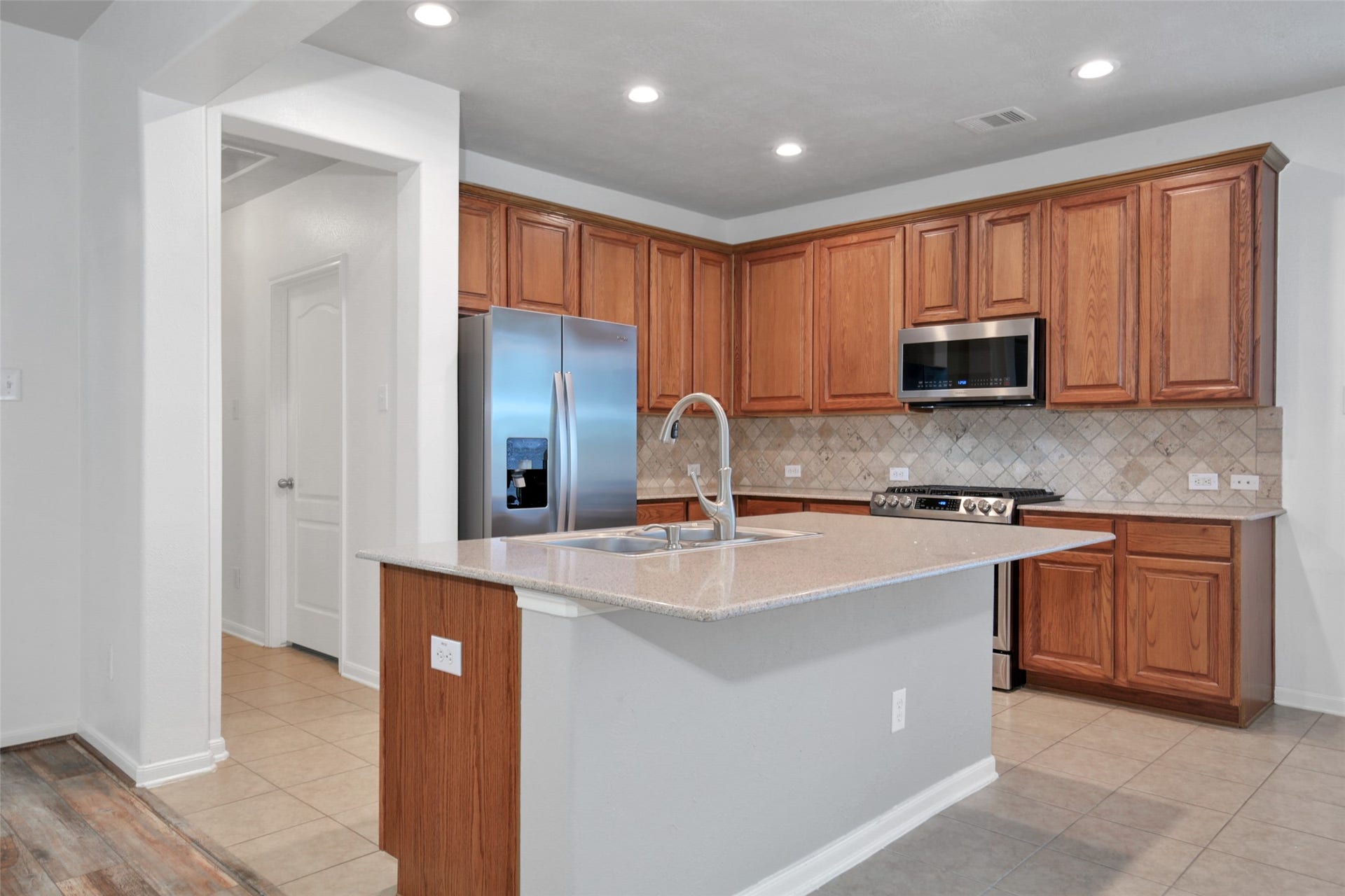 The kitchen is functional and pretty! Quartz countertops, Island with breakfast bar, stainless steel appliances, recessed lighting and adjacent pantry and utility room.