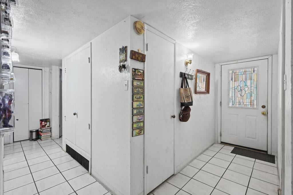 Bright entryway featuring a stained glass door, tiled floor, and ample storage with closets and hooks for convenience.