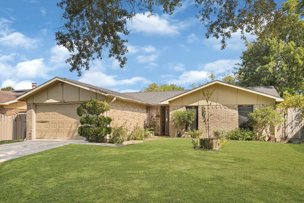 Charming single-story brick home with a spacious front yard, mature trees, and a welcoming entryway.