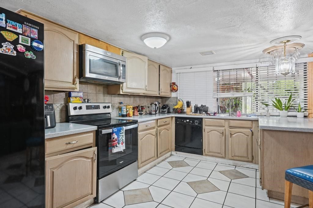 Kitchen with ample cabinetry, sleek stainless steel appliances, and a cozy breakfast nook by a large window offering natural light.