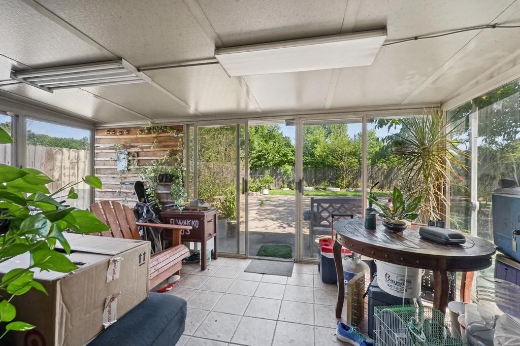 Sunroom with tiled floors and abundant natural light, perfect for relaxation and enjoying views of the lush backyard through large sliding glass doors.