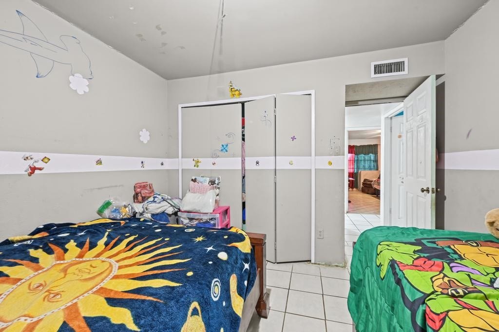Charming children's bedroom with playful decor, featuring tiled flooring, creative wall accents, and ample closet space.