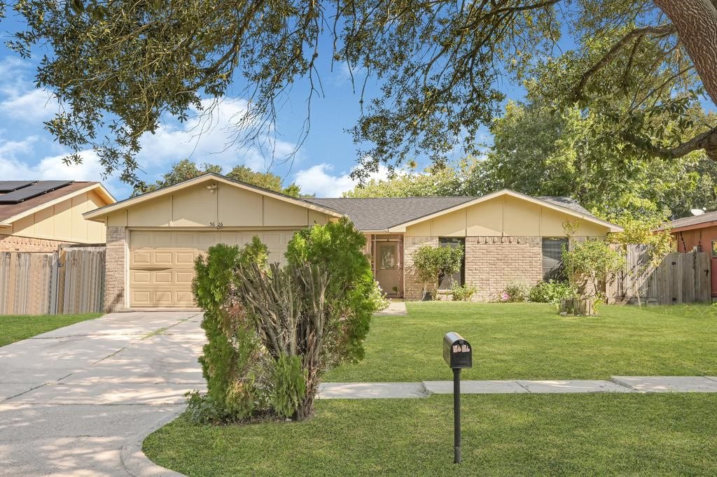 Charming single-story home with a brick facade, well-maintained lawn, and mature trees providing shade and curb appeal.