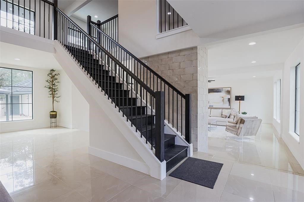 5614 Indian Circle, Houston, TX 77056 Alternate perspective of the grand entry showcasing a striking brick accent wall that leads into the open-concept living area. The blend of rich textures, from the tile flooring to the brick detail, creates a warm and inviting transition into the heart of the home.