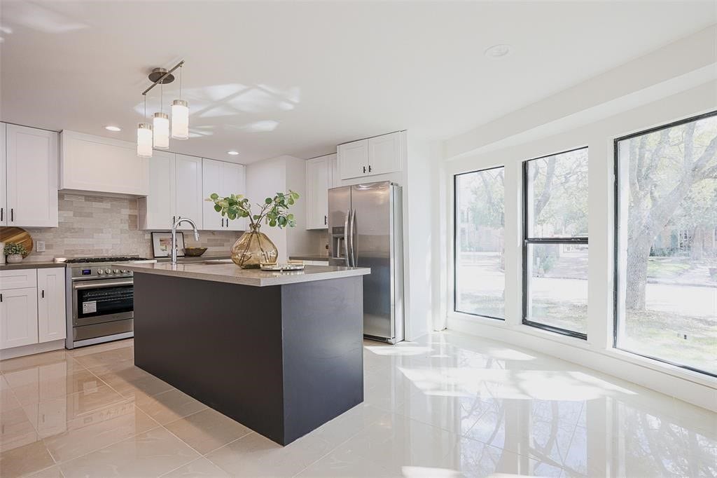5614 Indian Circle, Houston, TX 77056 Sophisticated kitchen with expansive quartz countertops, abundant cabinetry, and large bay windows that frame a picturesque view of the front yard. The design seamlessly blends functionality and style, creating a bright and inviting space perfect for both cooking and casual dining.