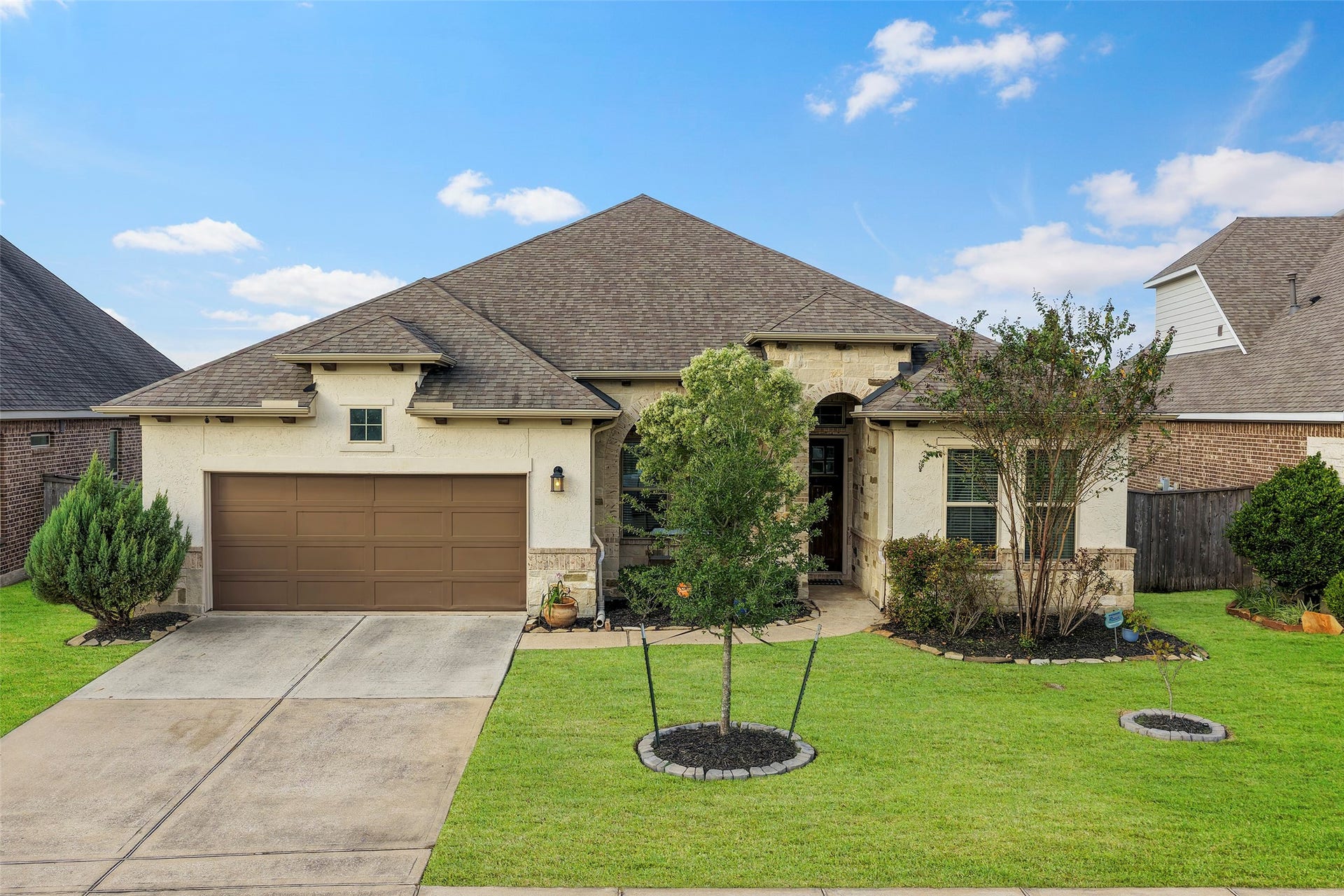 Charming single-story home with a welcoming facade, featuring a two-car garage and a beautifully landscaped front yard.
