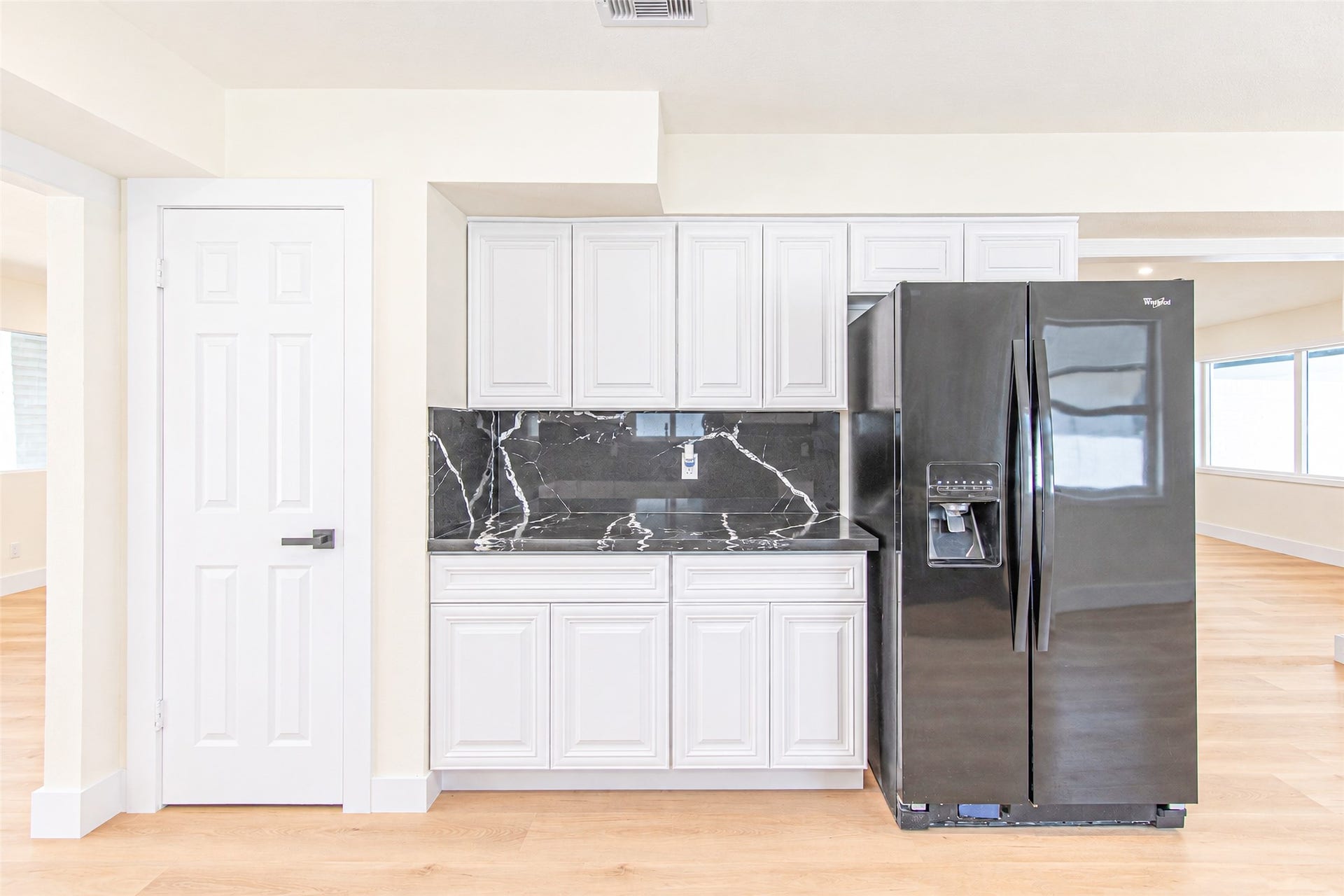 7623 Braes Meadow Drive, Houston, TX 77071 Experience modern elegance in this sleek kitchen, showcasing white cabinetry, a striking black quartz backsplash, and a stainless steel refrigerator with a convenient water dispenser.
