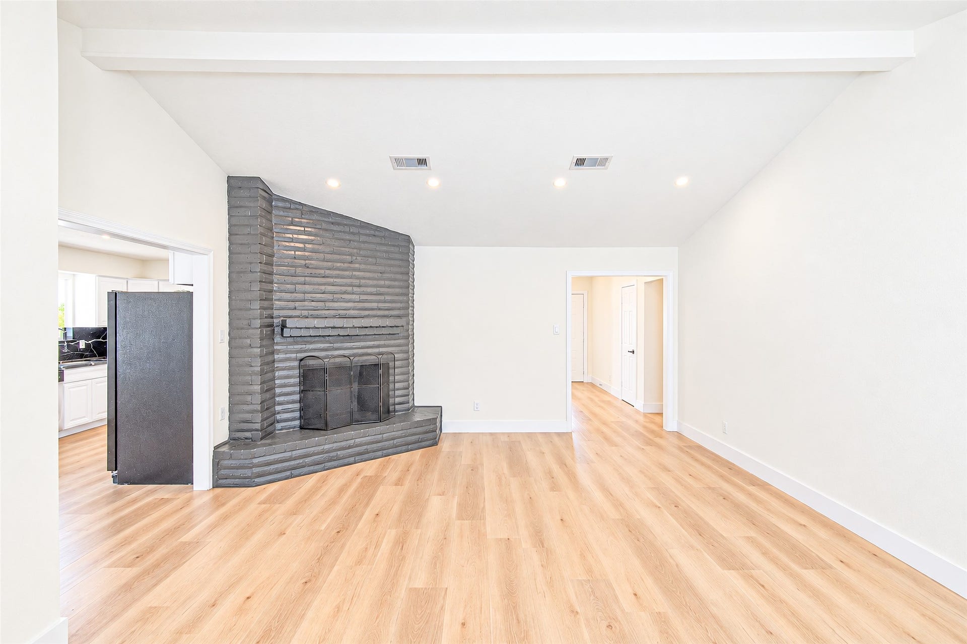 7623 Braes Meadow Drive, Houston, TX 77071 Spacious living area featuring a unique angled brick fireplace, high ceilings, and warm wood flooring, seamlessly connecting to the kitchen and hallway.