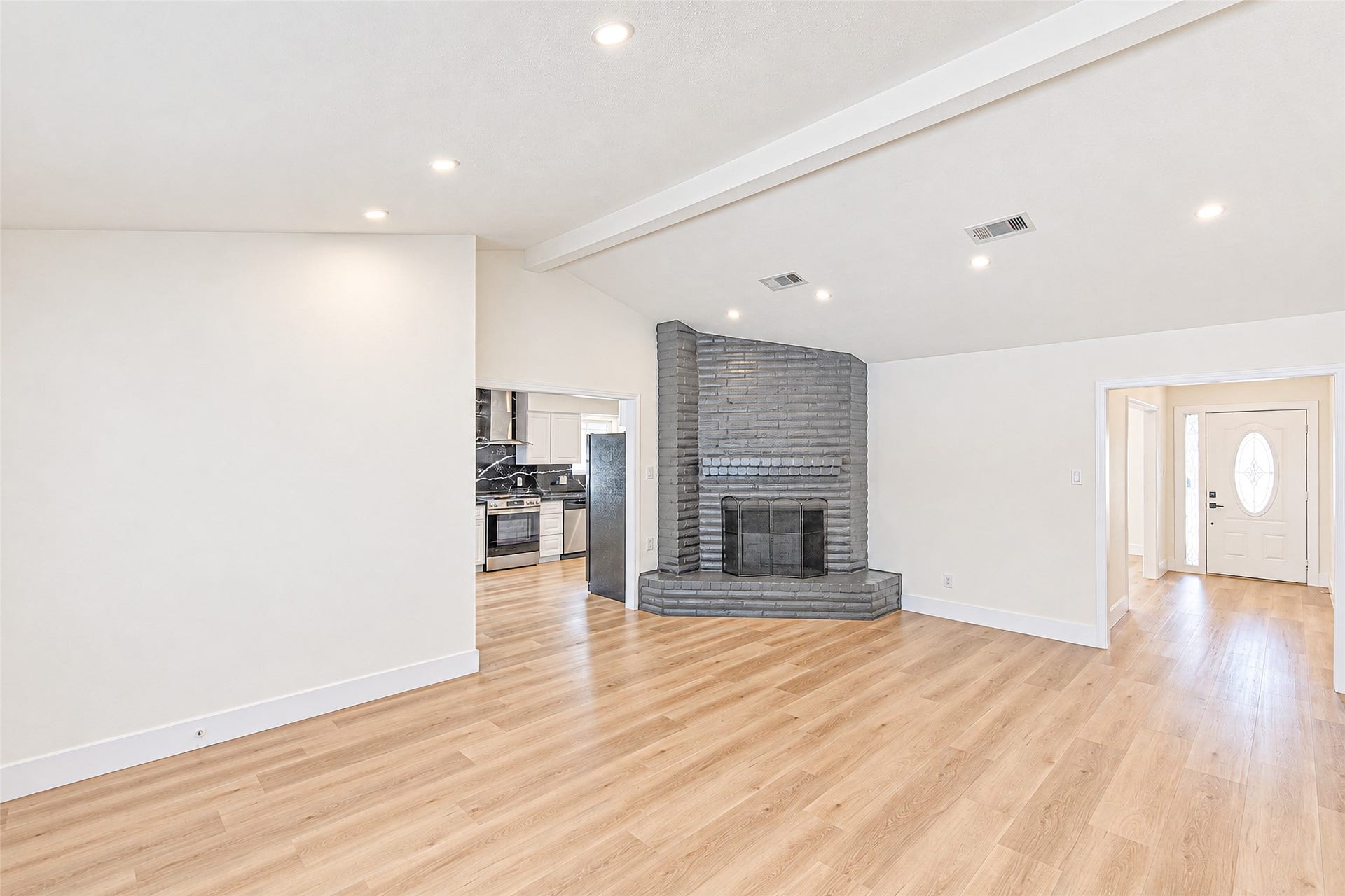 7623 Braes Meadow Drive, Houston, TX 77071 Spacious living area witluxury vinyl flooring, a striking gray brick fireplace, and recessed lighting, leading to a modern kitchen and bright entryway.