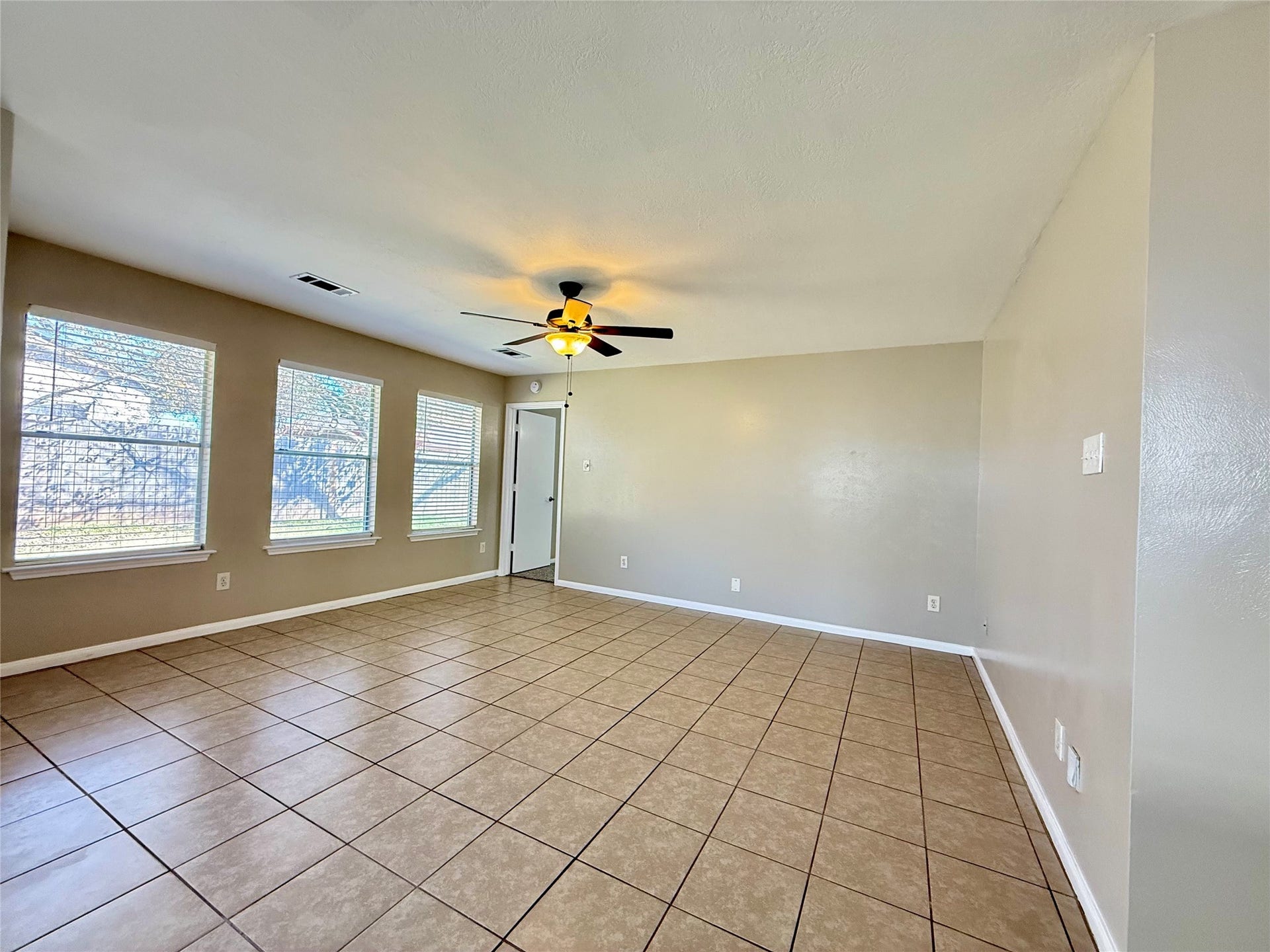 21514 Broadstone Drive, Katy, TX 77449 The spacious living room has large windows. The door leads into the primary bedroom.