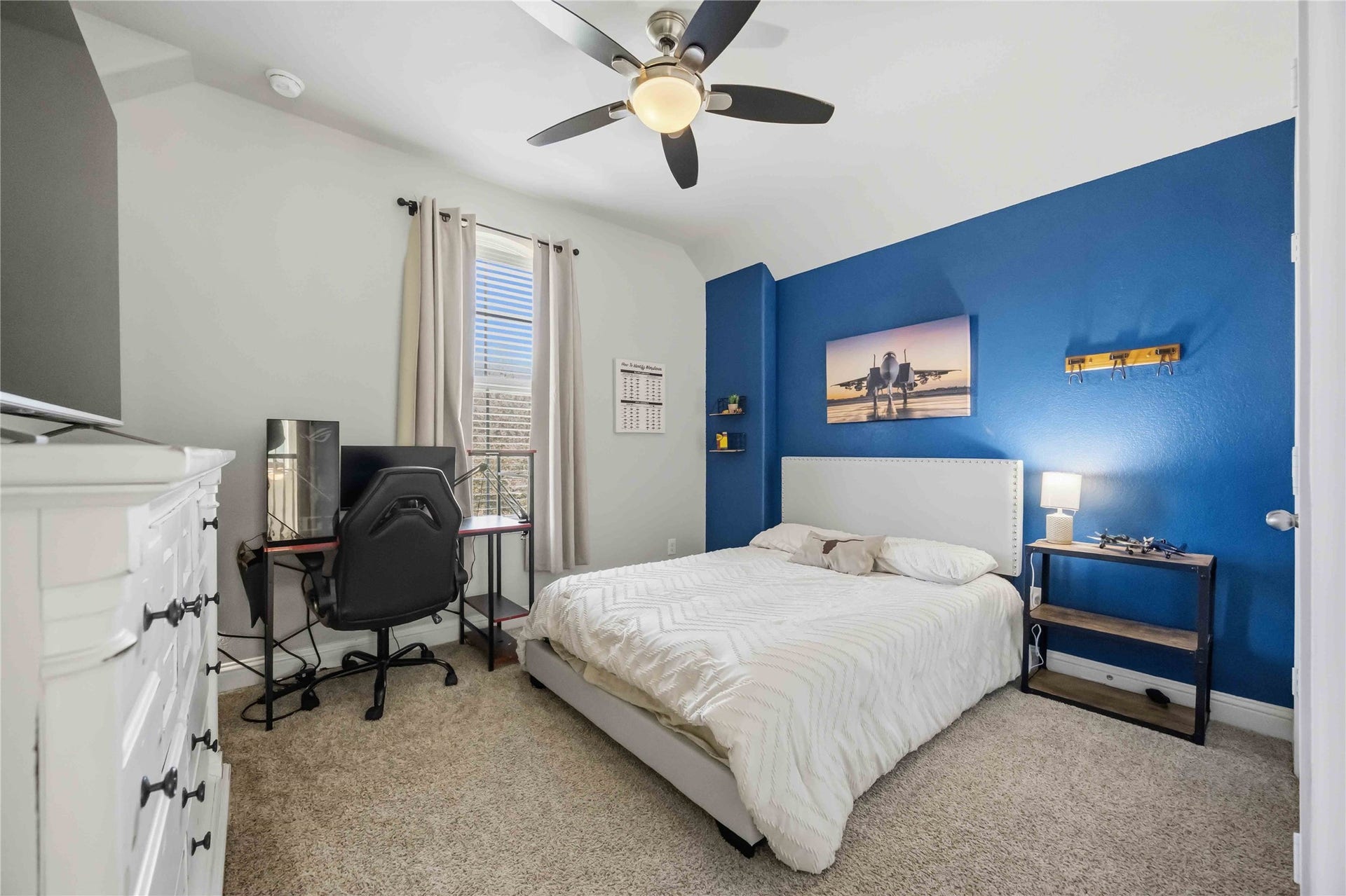 3152 Copeland Bend, Conroe, TX 77301 Upstairs, a bright bedroom with a blue accent wall has room for a bed and a workspace.