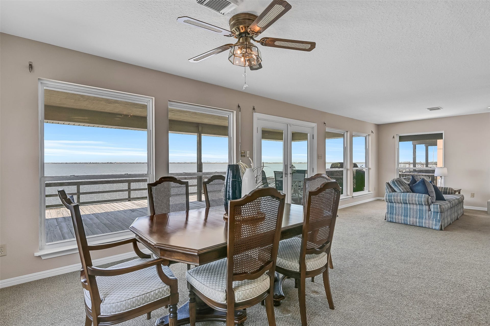 243 Isles End Road, #RR2, Tiki Island, TX 77554 Imagine enjoying every meal with a waterfront backdrop. Positioned alongside a wall of windows and French doors, the dining area offers front-row views of the bay and convenient access to the deck for seamless indoor-outdoor entertaining.