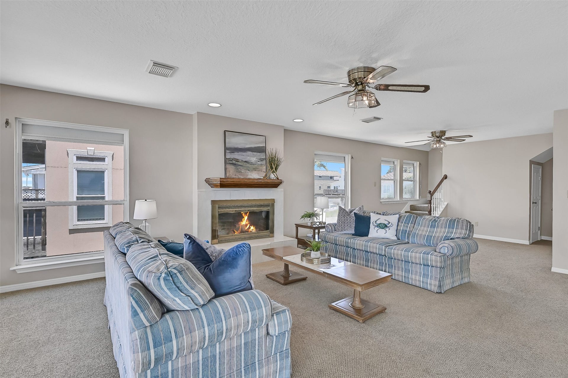 243 Isles End Road, #RR2, Tiki Island, TX 77554 Gather with family and friends in this spacious living area where bay views remain the focal point. Berber carpet, ceiling fans, recessed lighting, and a classic wood mantel create a warm and inviting space to relax after a day on the water.
