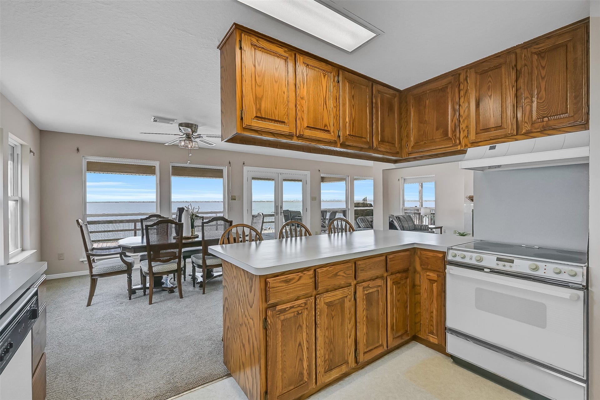 243 Isles End Road, #RR2, Tiki Island, TX 77554 A large breakfast bar provides additional seating and serves as a natural gathering spot for guests. Oak cabinetry, plentiful storage, white appliances, and a walk-in pantry create a practical workspace designed for easy coastal living.