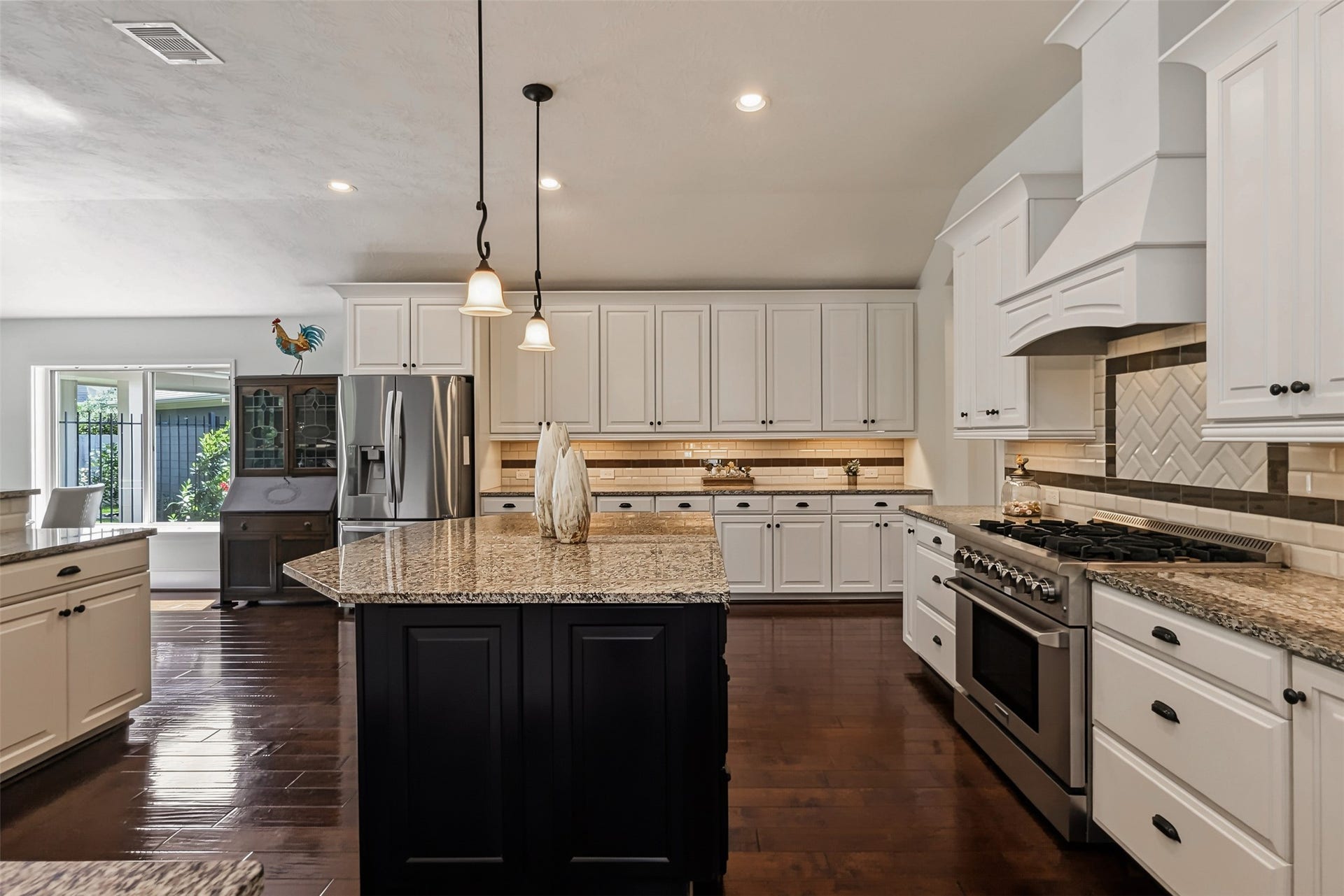 Elegant kitchen featuring 42-inch wood cabinets, granite countertops, a custom vent hood, and a high-end 6-burner range and under cabinet lighting