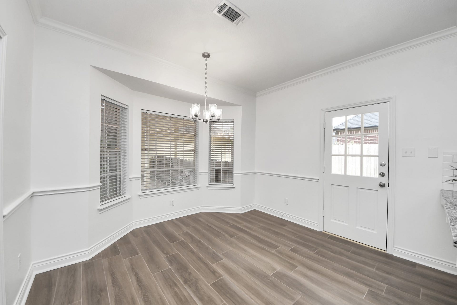 large bay windows, and a stylish chandelier, leading to a charming door with driveway access.