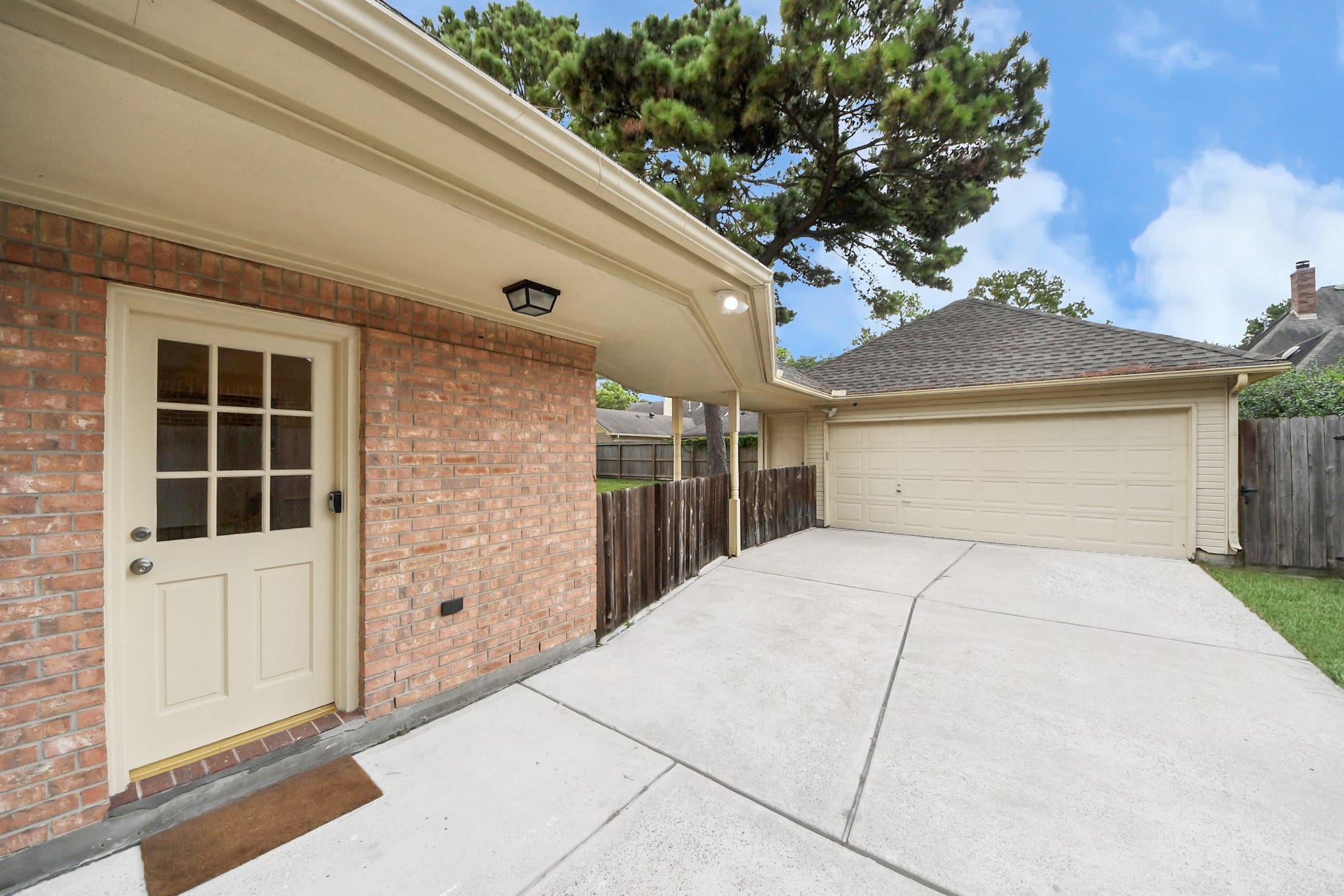 Spacious driveway leads to a detached two-car garage, framed by a charming brick exterior.