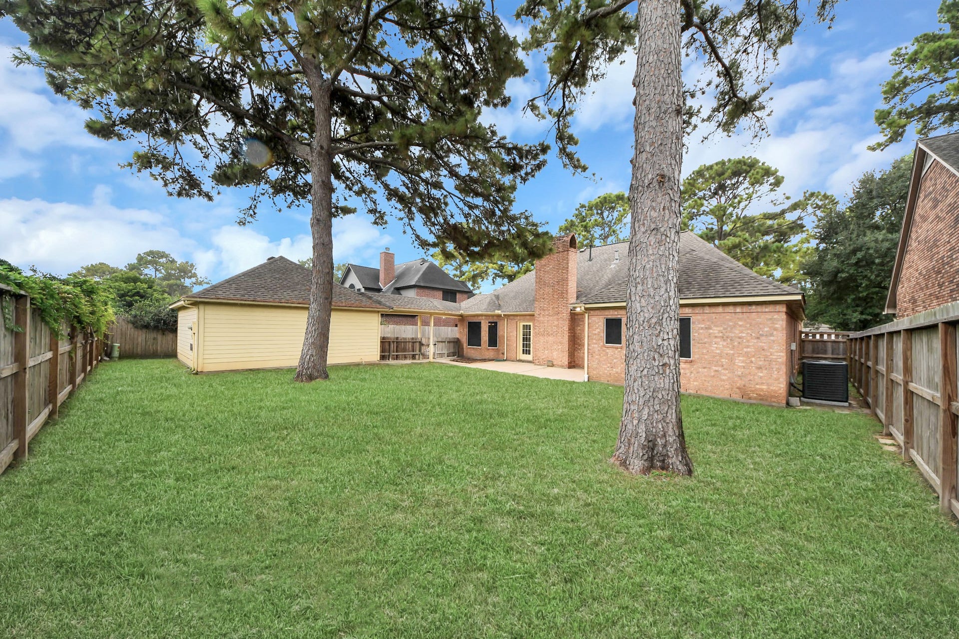 Spacious backyard with mature trees and a privacy fence, perfect for outdoor activities and relaxation.