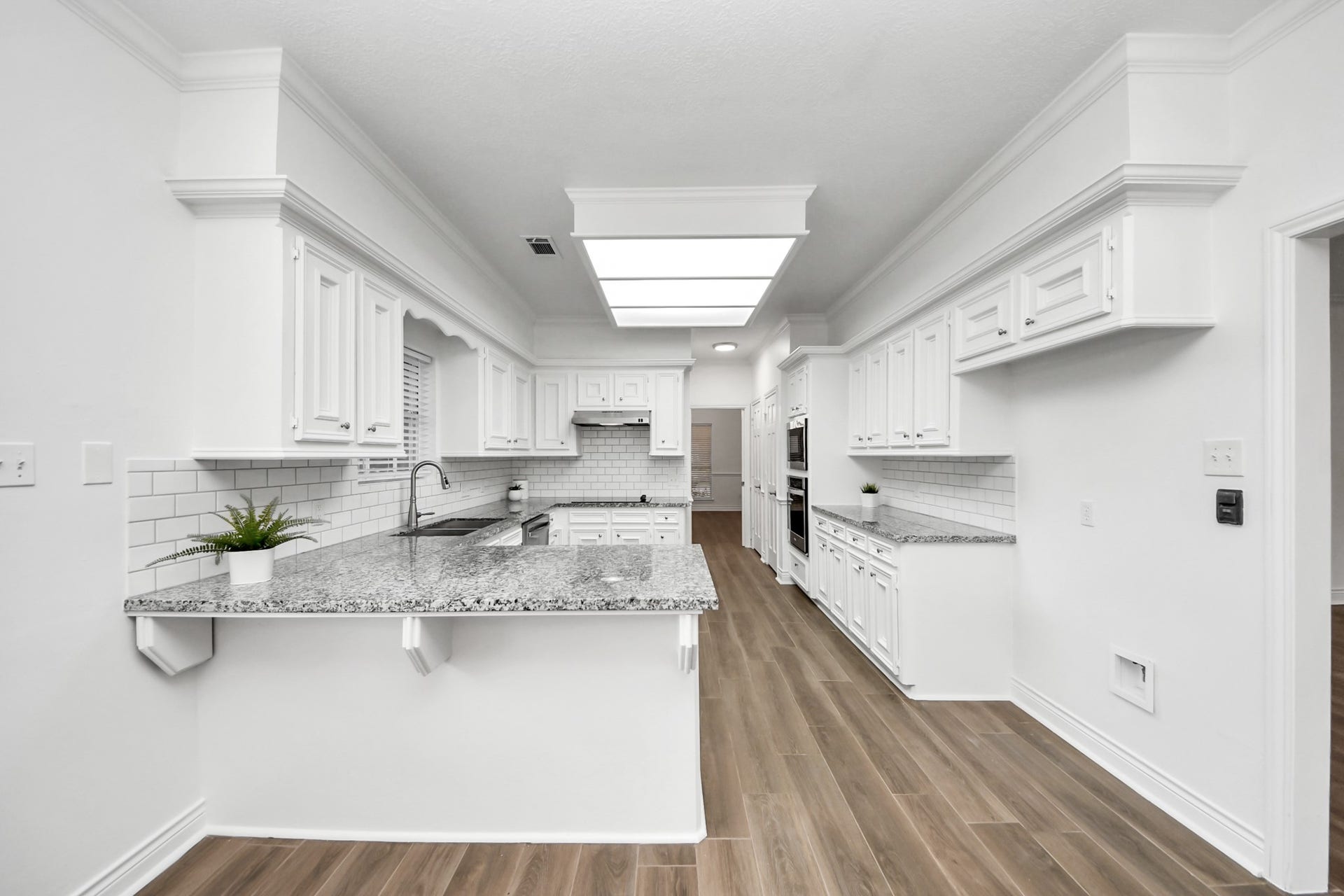 Large spacious kitchen featuring white cabinetry, granite countertops, and a stylish tile backsplash.
