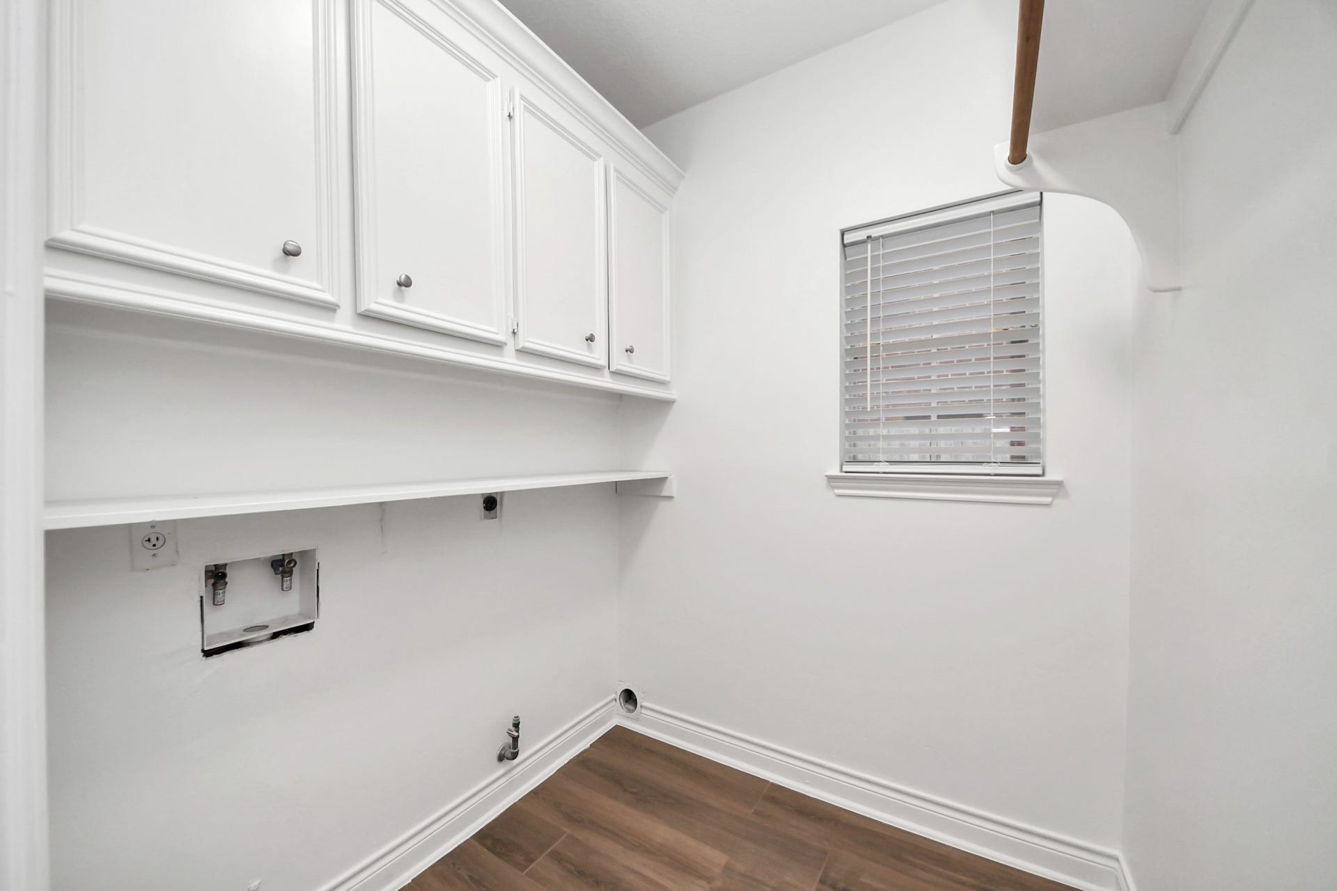 Laundry room featuring ample cabinetry, a convenient utility shelf, and a window for natural light.
