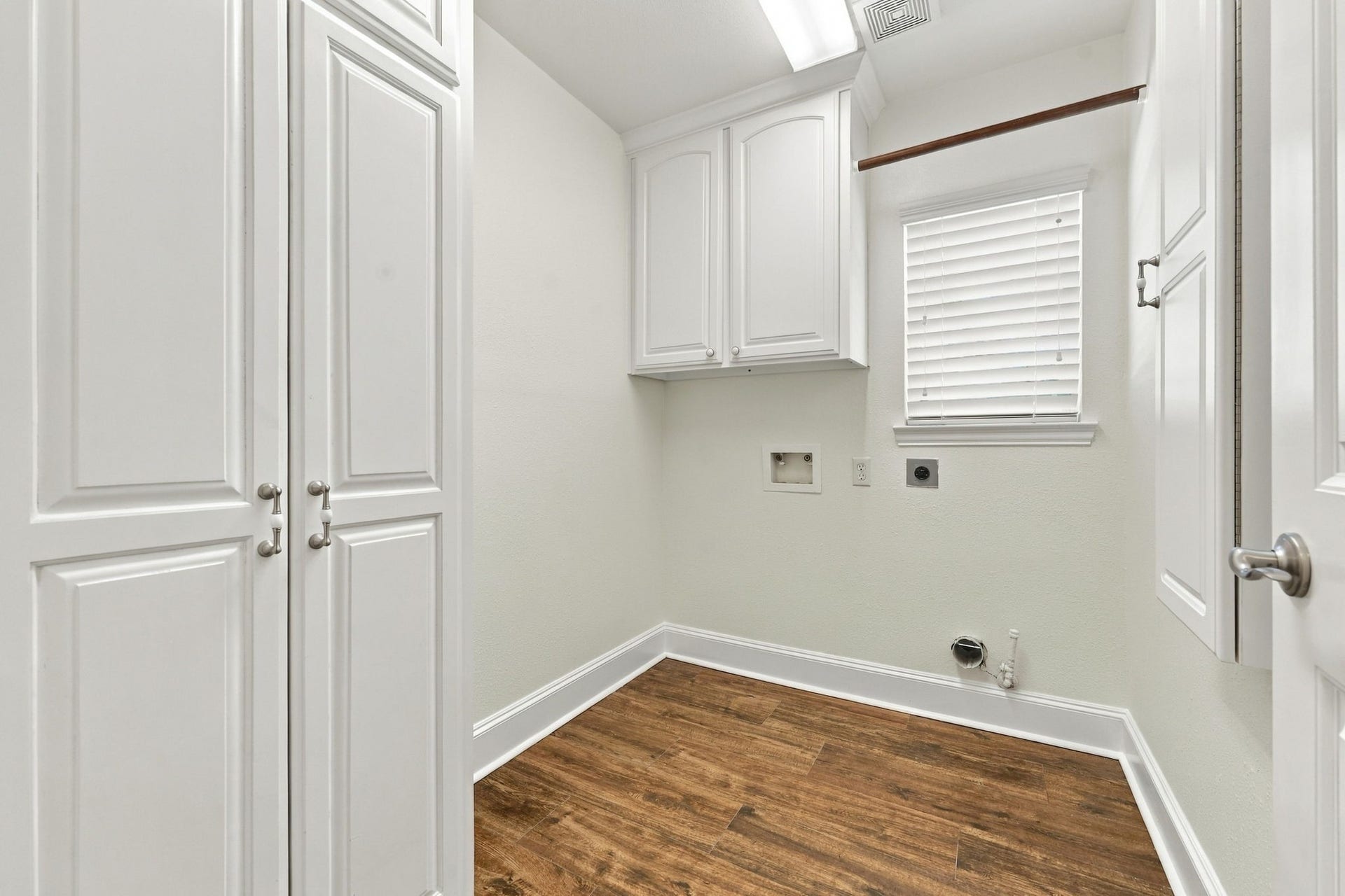 33211 Woodton Court, Weston Lakes, TX 77441 The Laundry Room is conveniently located just to the right of the Dry Bar and features a built-in ironing board, abundant storage cabinetry, and both gas and electric connections for your choice of dryer. A window with 2-inch blinds provides natural light, creating a bright and functional workspace.
