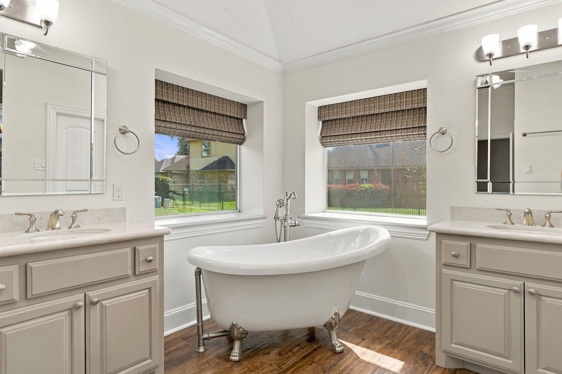 33211 Woodton Court, Weston Lakes, TX 77441 The freestanding soaking tub is beautifully positioned in the corner and features a brushed nickel faucet with a separate handheld wand. Framed by two windows with elegant Roman shades, this serene space creates the perfect setting to relax and unwind.