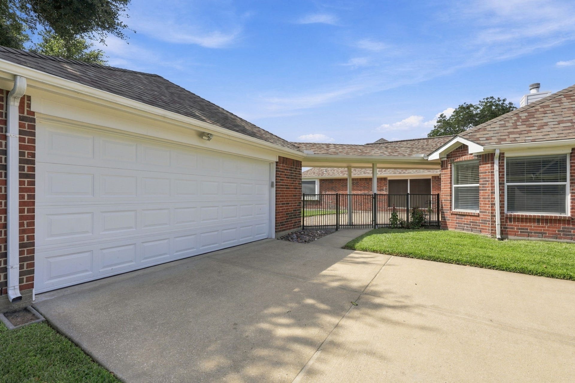 33211 Woodton Court, Weston Lakes, TX 77441 A wrought-iron fence and gate enclose the breezeway leading to the Backyard, providing privacy and security while offering easy access to the spacious back patio area.