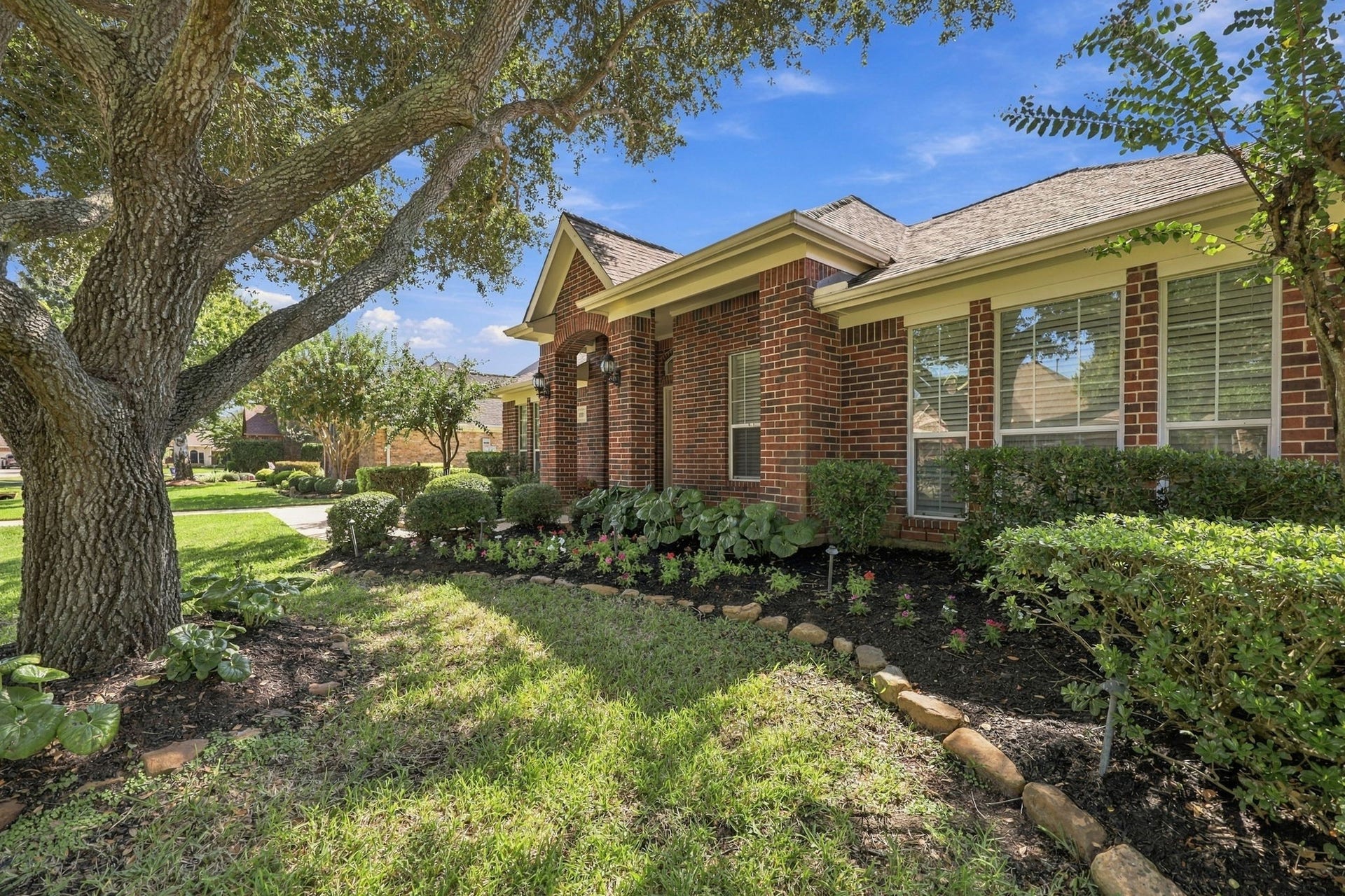 33211 Woodton Court, Weston Lakes, TX 77441 The mature landscaping is beautifully bordered with natural stone and features a variety of lush shrubs and greenery, creating a warm, inviting, and well-manicured setting that enhances the homes exceptional curb appeal.
