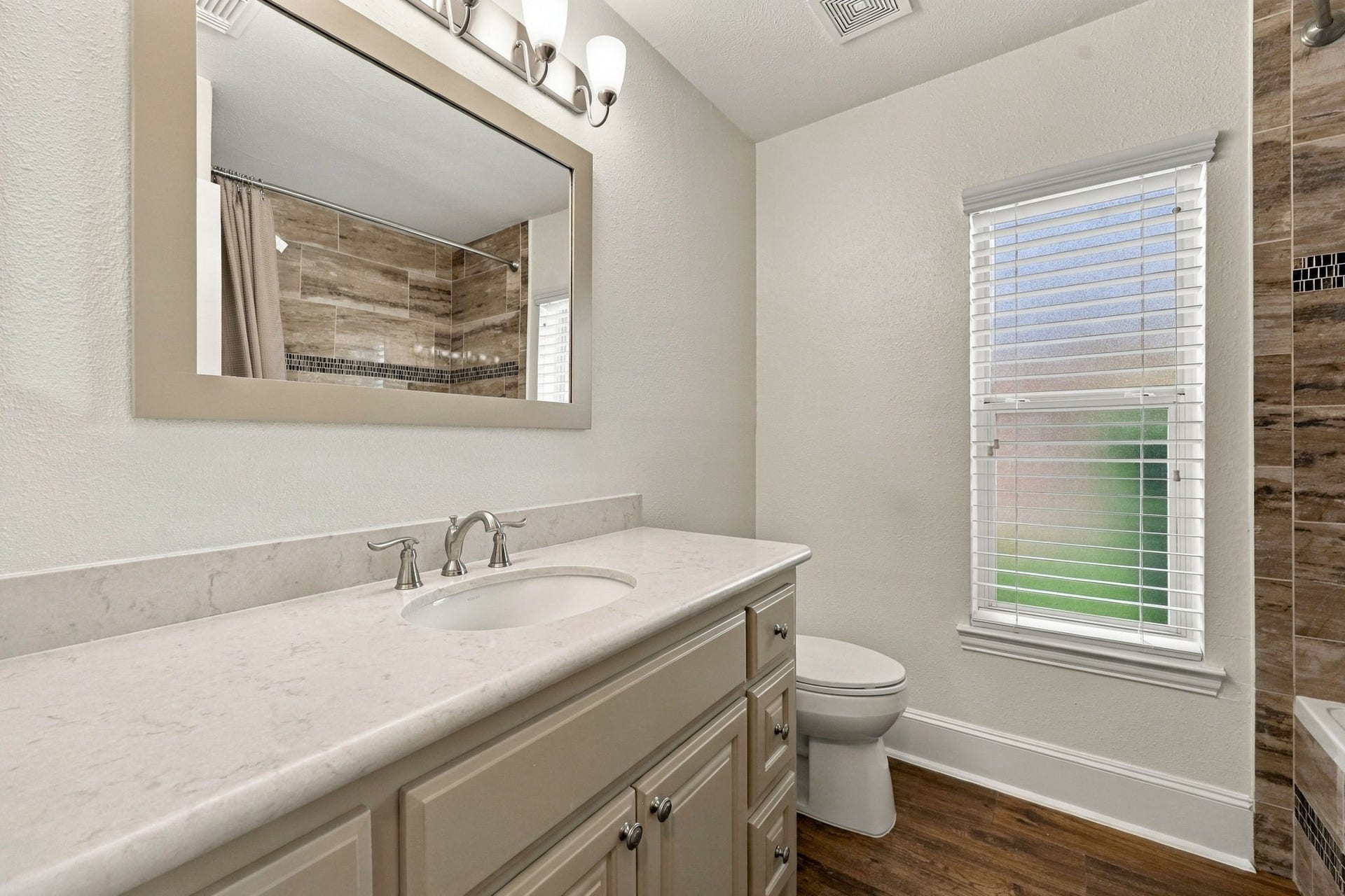 33211 Woodton Court, Weston Lakes, TX 77441 This Full Bath serves the two Secondary Bedrooms featured in the previous photos and is beautifully appointed with Quartz countertops, an undermount sink, a framed mirror, widespread brushed nickel faucet, and coordinating light fixture and hardware. Elegant finishes create a stylish and cohesive space.