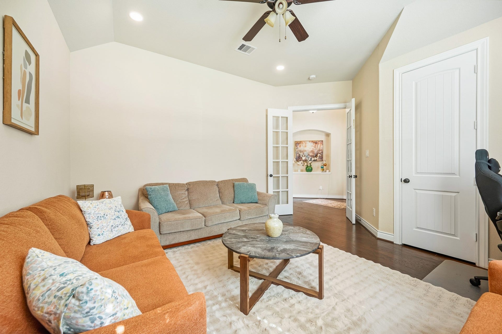 25610 Buckley Bluff Lane, Katy, TX 77494 Embrace the charm of a cozy living area with warm-toned sofas and a central round coffee table, effortlessly flowing into a bright hallway through elegant French doors.