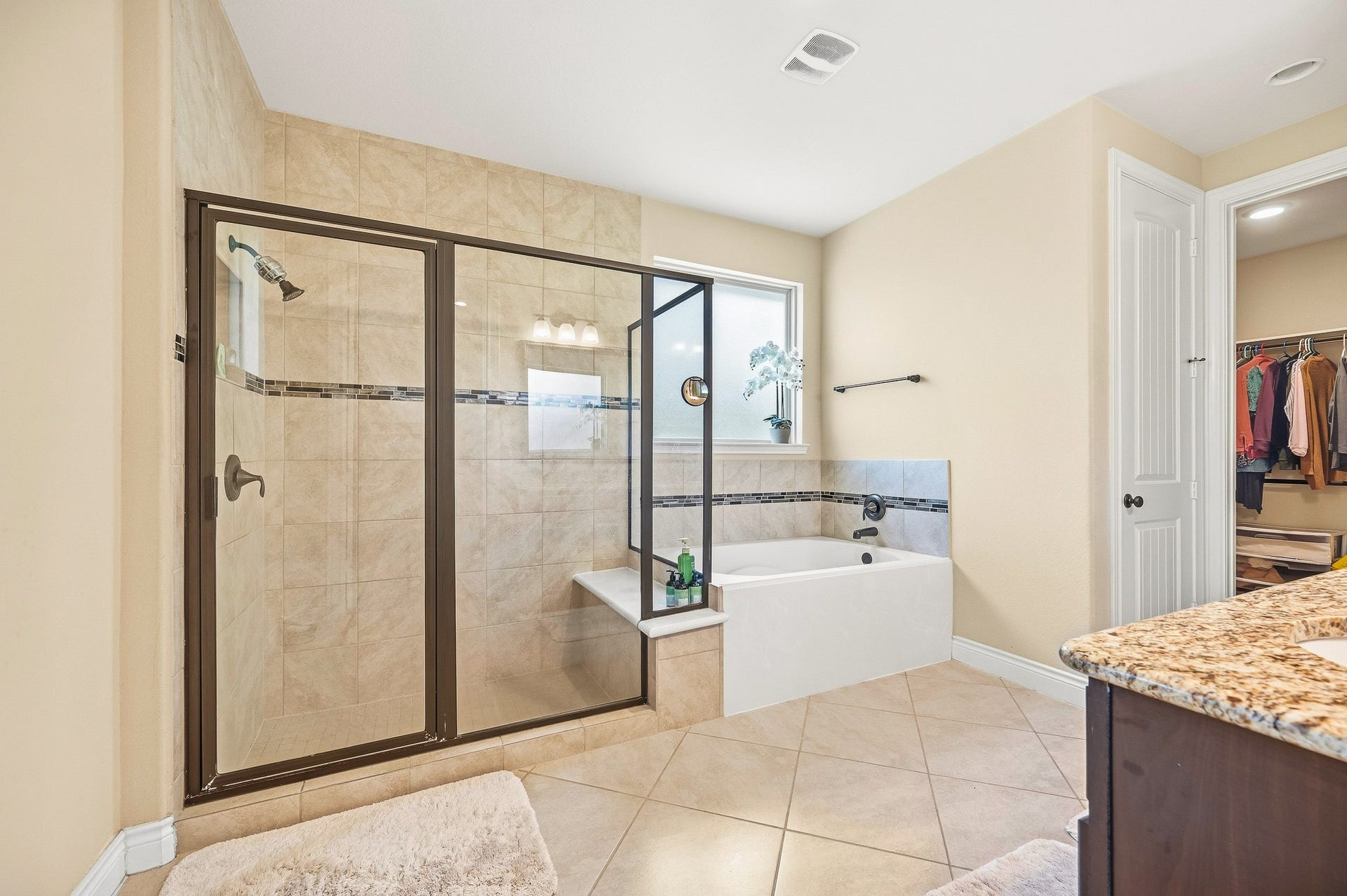 25610 Buckley Bluff Lane, Katy, TX 77494 Experience luxury in this elegant bathroom featuring a spacious glass-enclosed shower, a relaxing bathtub with stylish tiled surround, and the convenience of an adjoining walk-in closet.