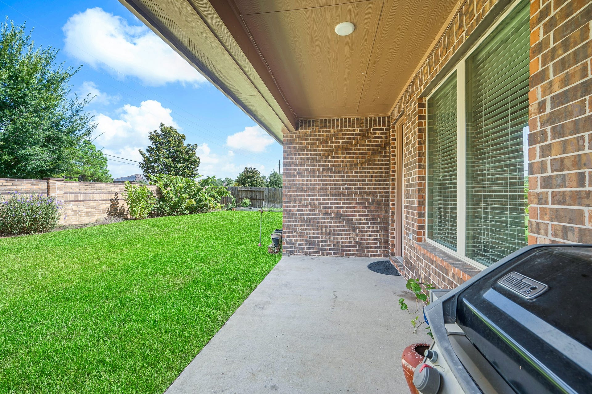 25610 Buckley Bluff Lane, Katy, TX 77494 A charming covered patio with elegant brick accents overlooks a lush, well-maintained backyard, perfect for outdoor gatherings and relaxation.