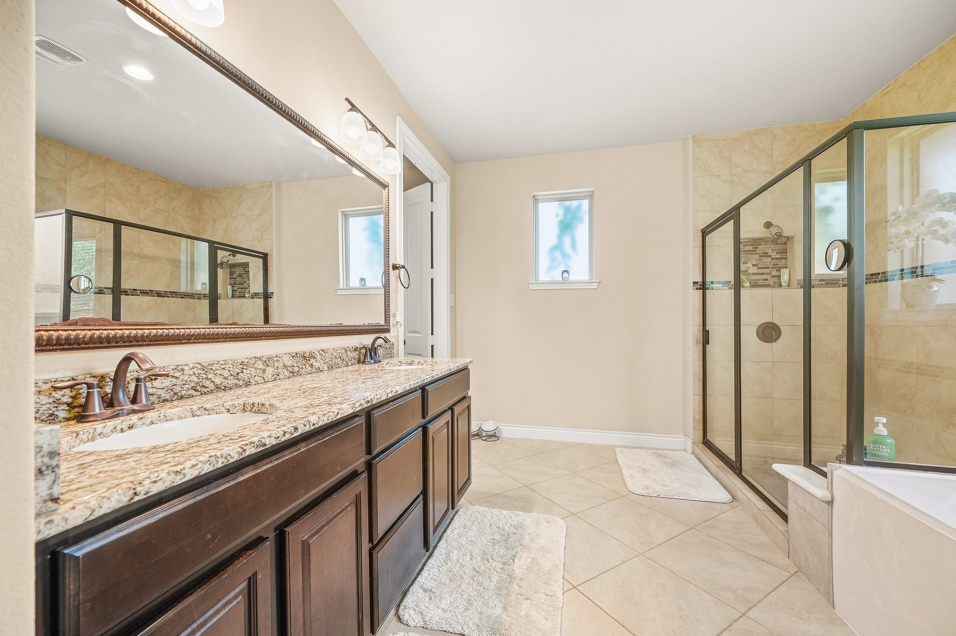 25610 Buckley Bluff Lane, Katy, TX 77494 Experience elegance in this luxurious bathroom featuring a spacious double vanity with granite countertops, a large glass-enclosed shower, and neutral tile flooring for a sophisticated touch.