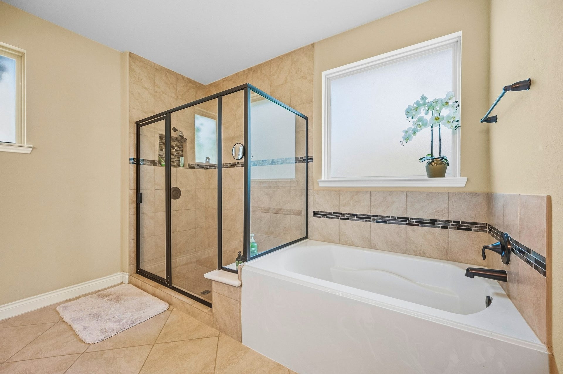 25610 Buckley Bluff Lane, Katy, TX 77494 Experience the elegance of a bathroom with a spacious glass-enclosed shower and relaxing bathtub, adorned with stylish tile accents and bathed in abundant natural light.