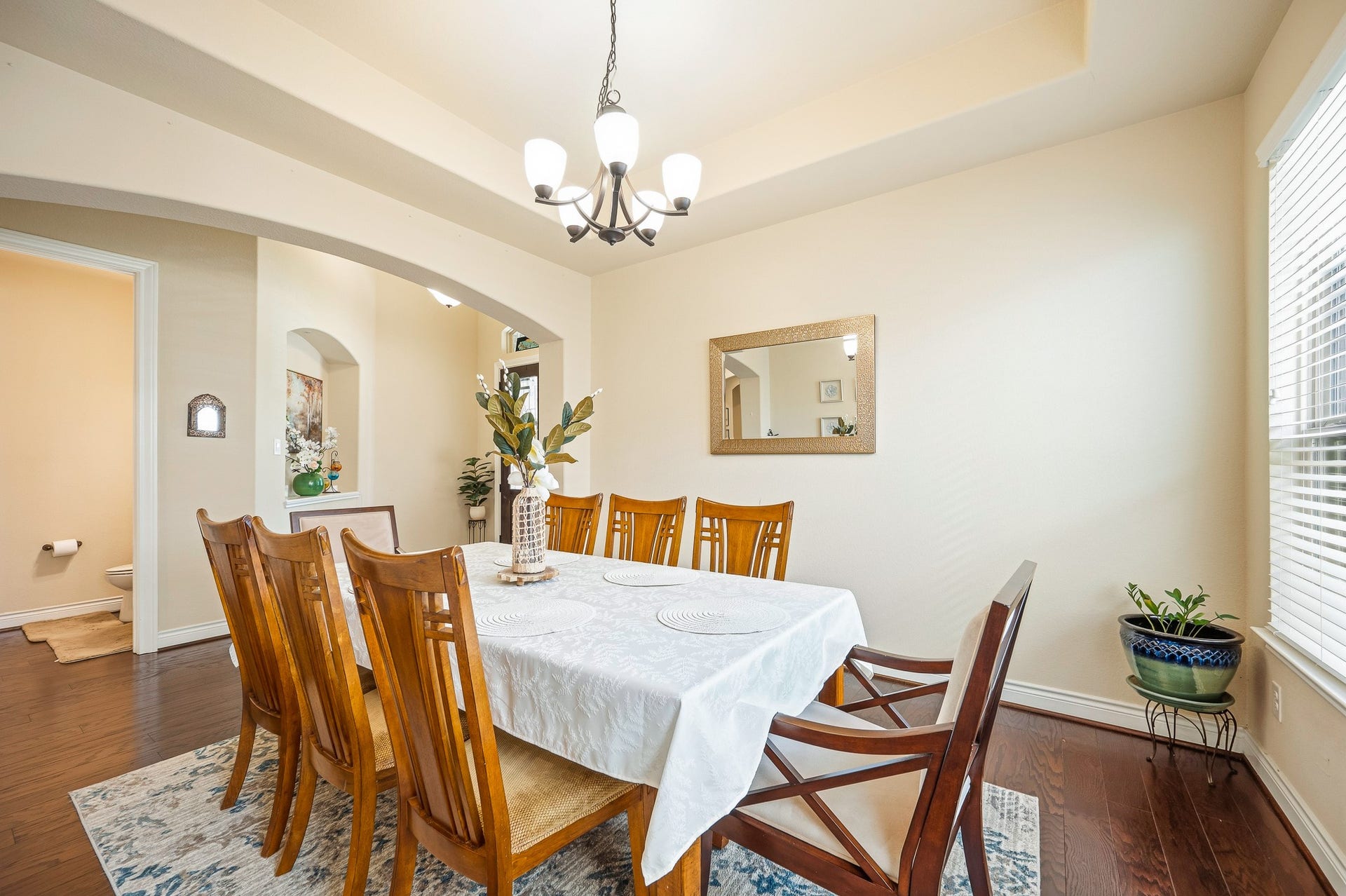 25610 Buckley Bluff Lane, Katy, TX 77494 Elegant dining room featuring a stylish chandelier, warm wood flooring, and ample natural light from large windows, perfect for hosting gatherings.