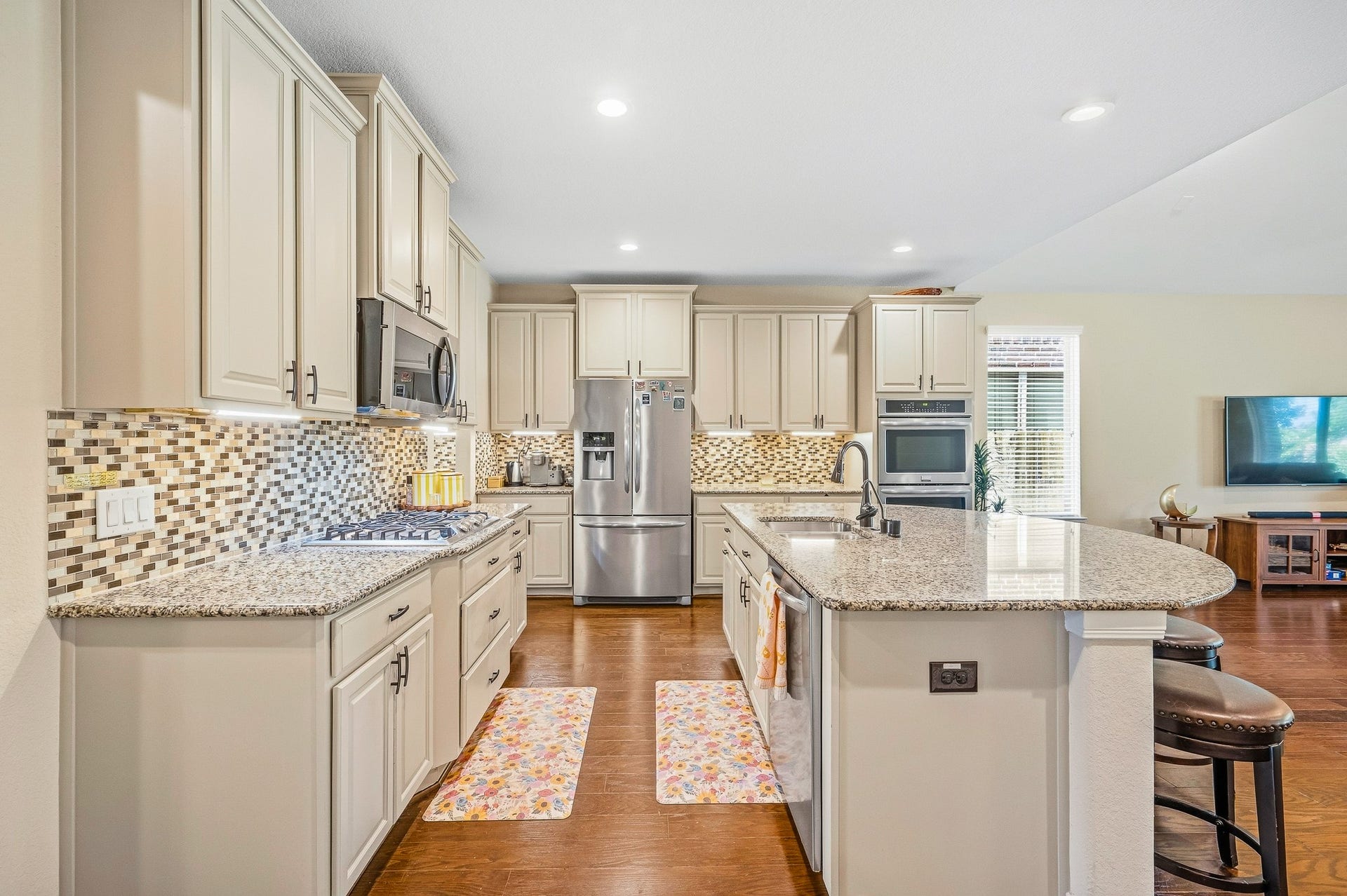 25610 Buckley Bluff Lane, Katy, TX 77494 Experience a chef's dream kitchen with elegant granite countertops, a spacious island with seating, stainless steel appliances, and a chic mosaic tile backsplash, perfect for culinary enthusiasts.