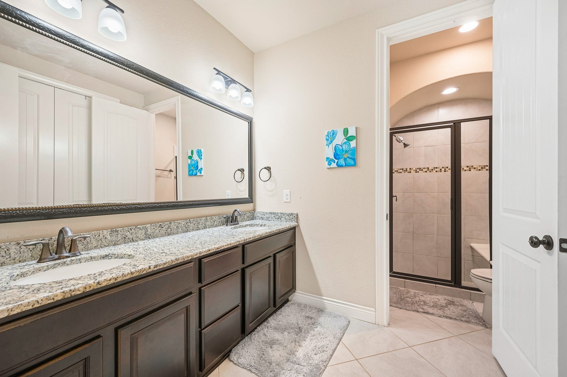25610 Buckley Bluff Lane, Katy, TX 77494 Experience elegance in this bathroom with a spacious dual-sink vanity topped with granite, a large framed mirror, and a walk-in shower featuring stylish tile detailing.