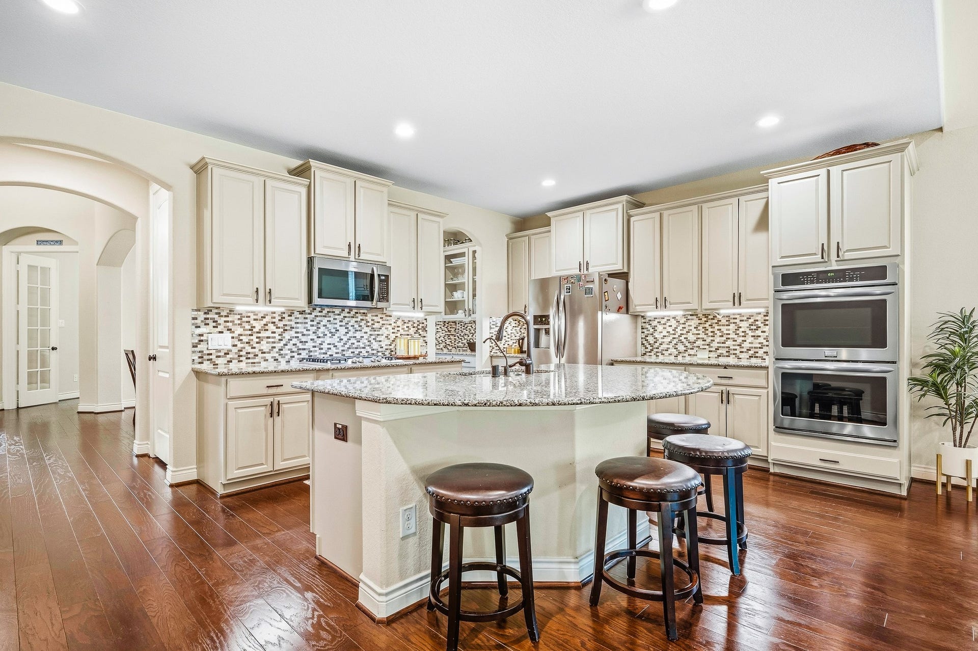 25610 Buckley Bluff Lane, Katy, TX 77494 Experience culinary luxury in a spacious gourmet kitchen featuring elegant cabinetry, granite countertops, a central island with seating, stainless steel appliances, and a stylish mosaic backsplash.