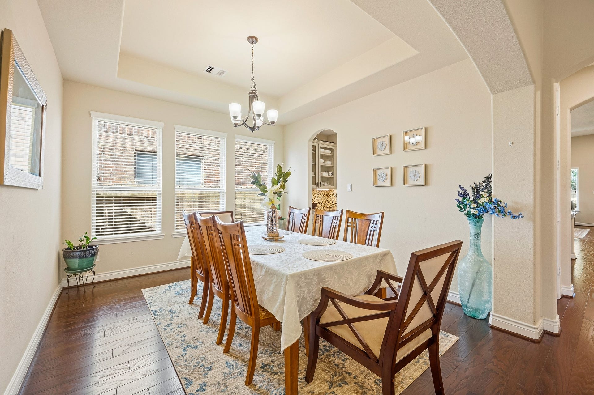 25610 Buckley Bluff Lane, Katy, TX 77494 Elegant dining room with warm hardwood floors, abundant natural light from large windows, and a stylish chandelier above a spacious table, perfect for gatherings.