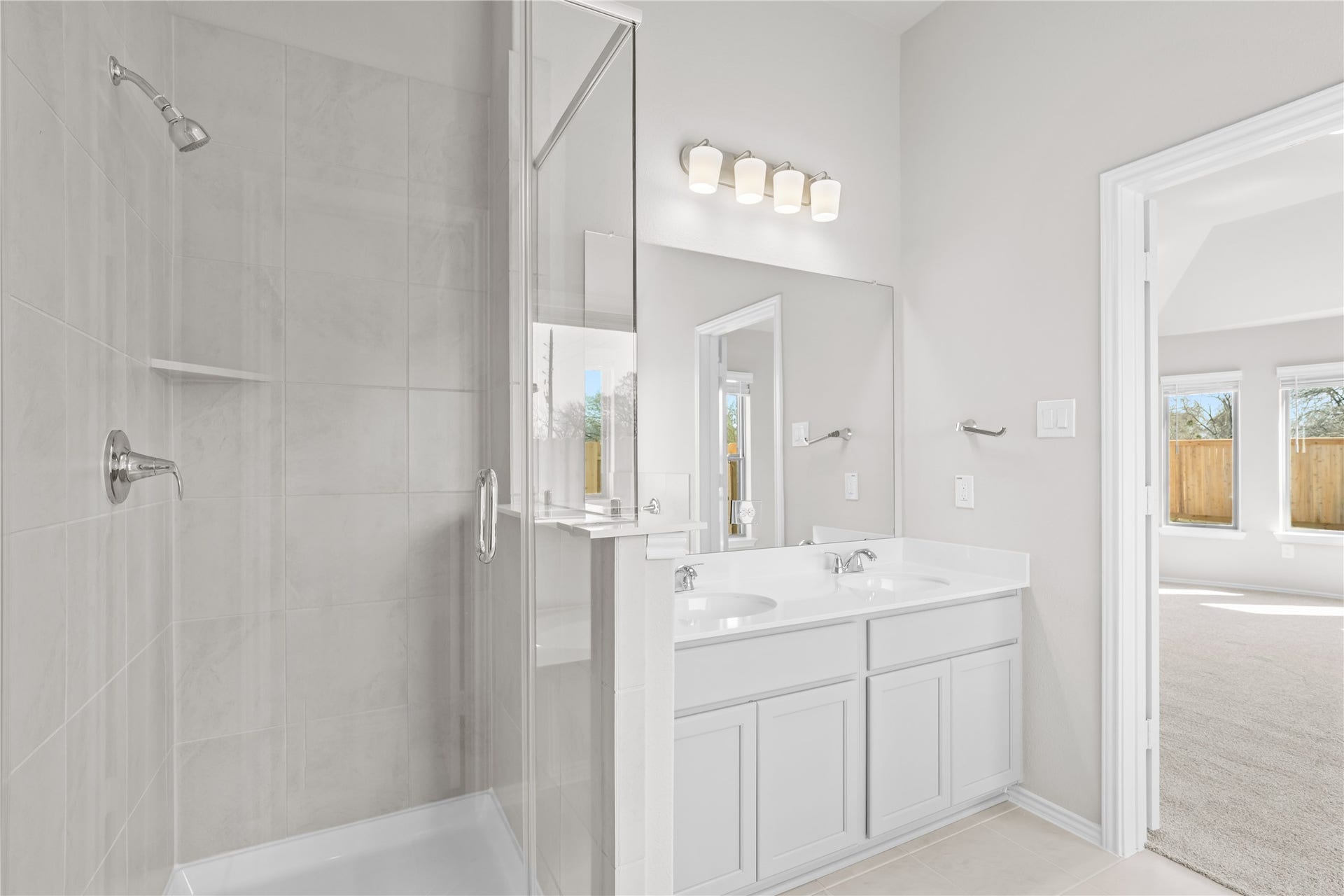 An alternate view of the primary bath highlights the tile surround shower and double vanity.
