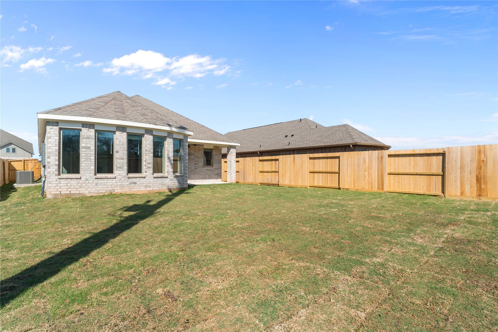 A rear view showcases the primary suite's wall of windows and the spacious fenced yard.