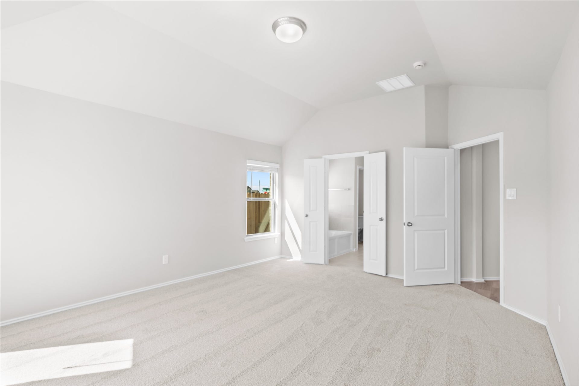The primary suite offers generous proportions, with double doors opening to the ensuite bath and walk in closet.