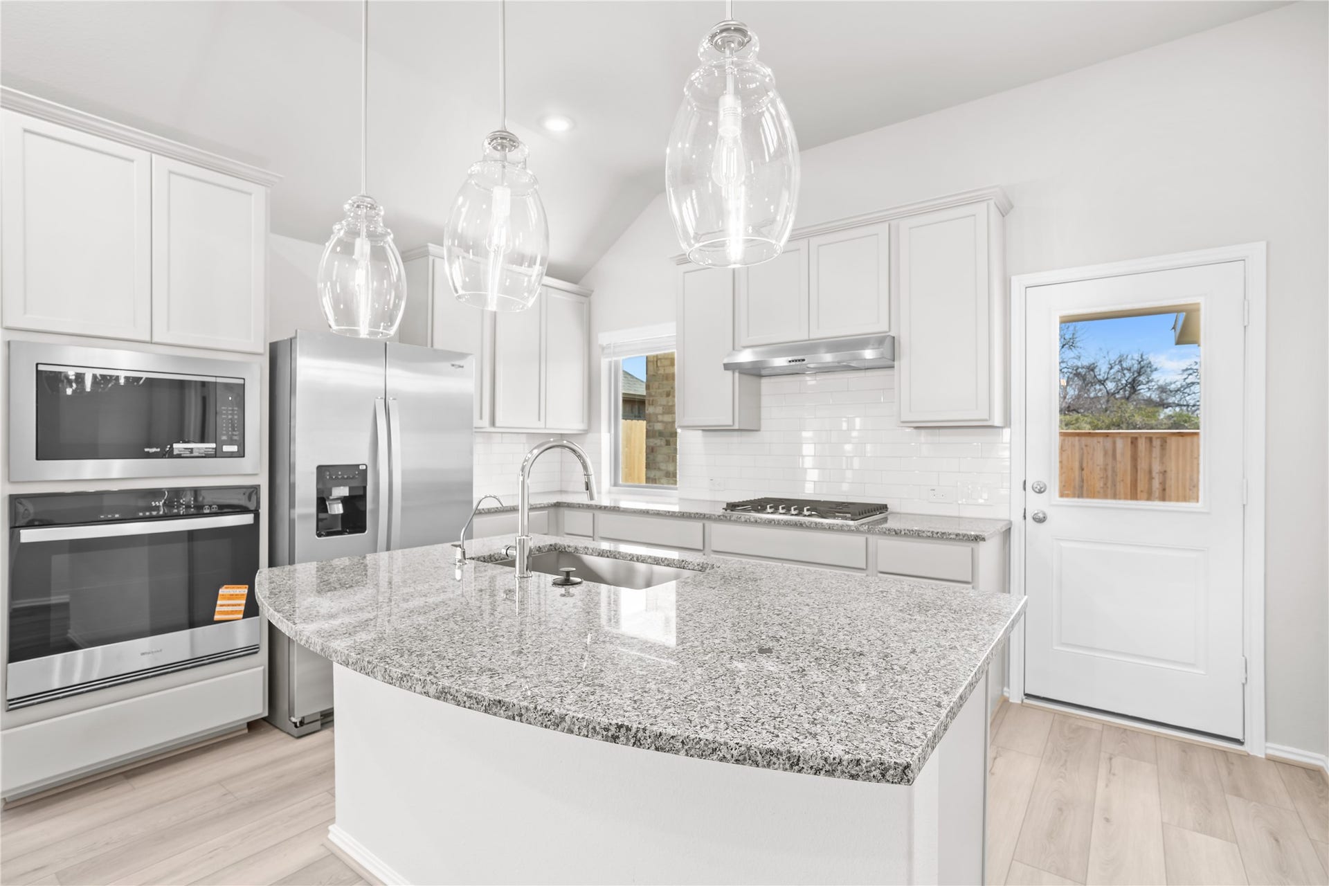 The curved island offers breakfast bar seating and an undermount sink, alongside a built in oven and microwave.