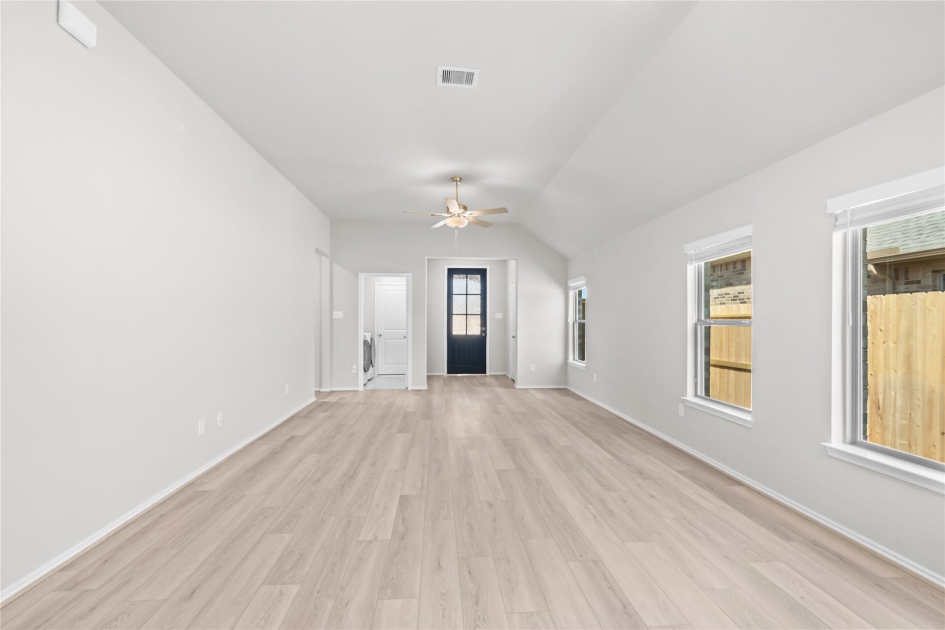 Looking back toward the entry, the family room is bathed in natural light beneath a soaring vaulted ceiling.