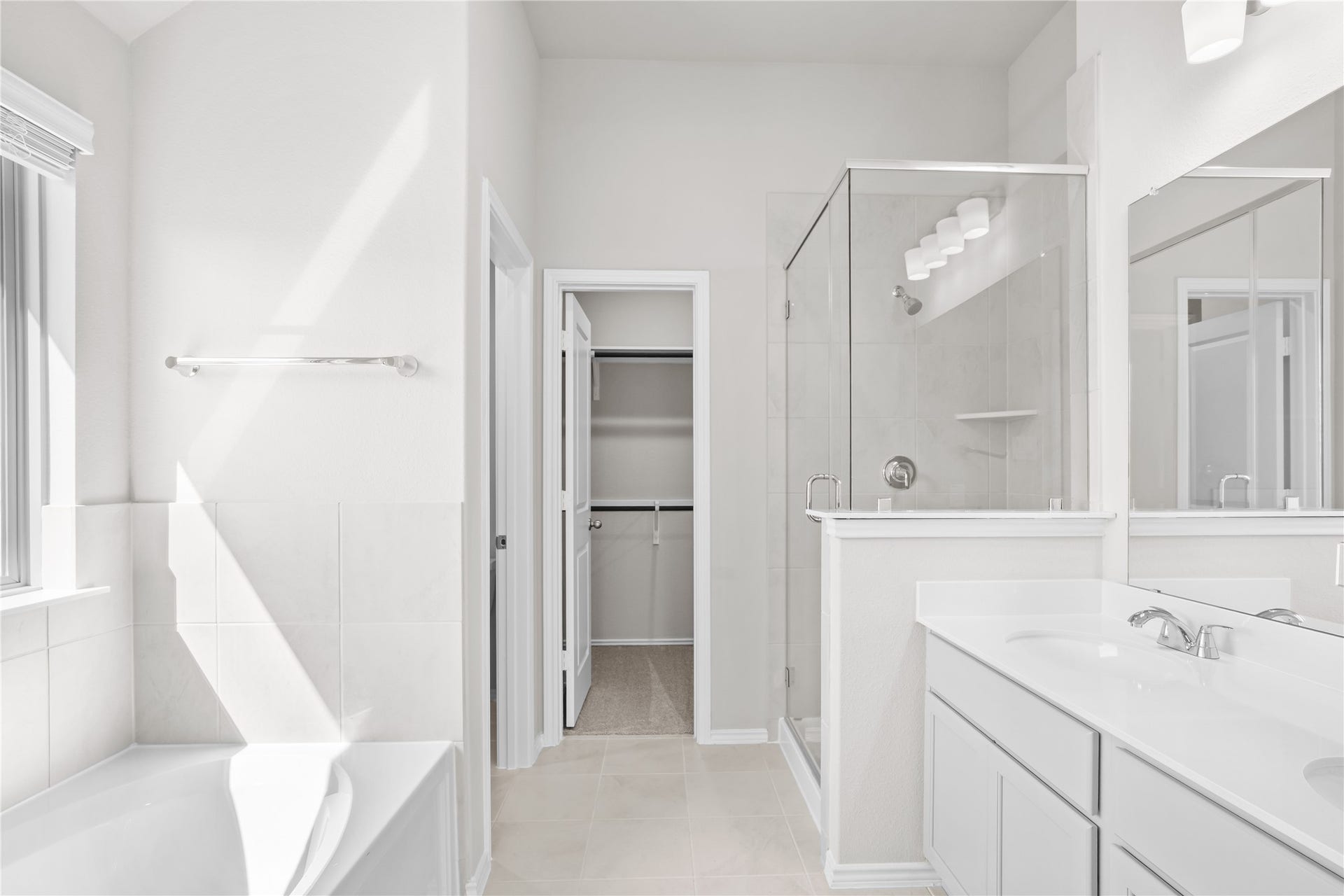The primary bath features a soaking tub, a separate glass enclosed shower and a double vanity, with direct access to the walk in closet.