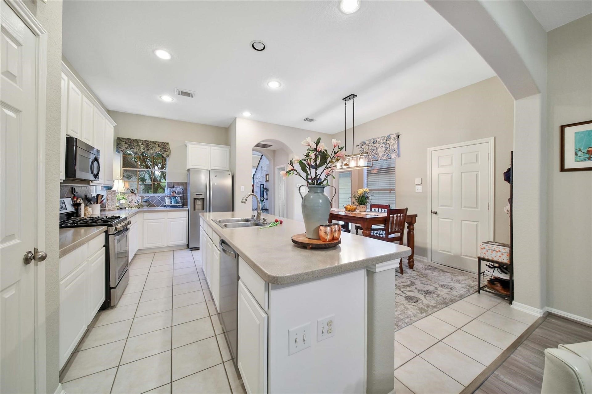 This photo shows a spacious, well-lit kitchen with modern appliances, ample counter space, and a breakfast bar, leading into a cozy dining area. The open floor plan and neutral color palette offer a blank canvas for personalization.
