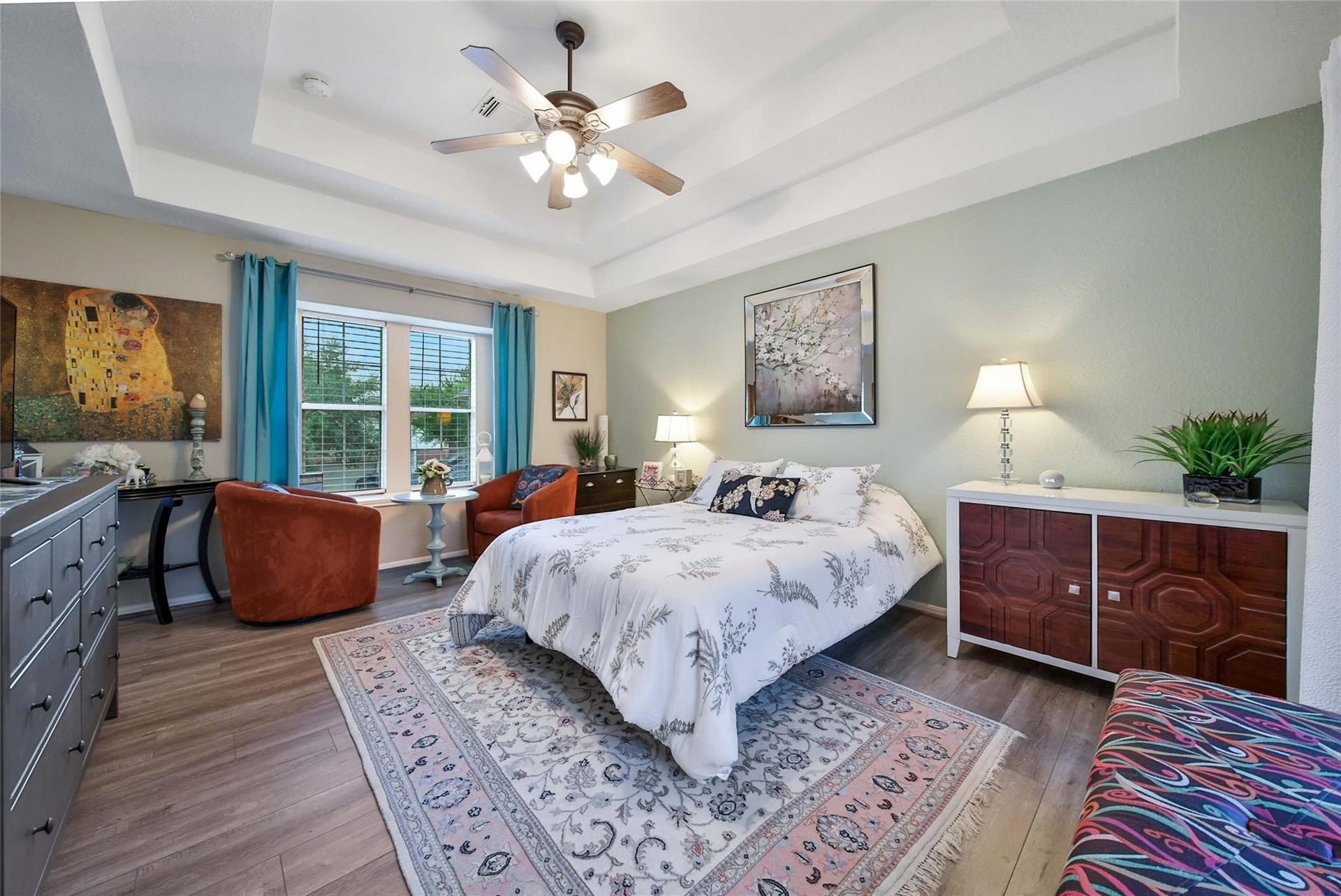 This is a bright, modern bathroom with dual vanities, ample storage, and a view into an adjoining bedroom. The space features contemporary lighting and patterned floor tiles for a touch of elegance.